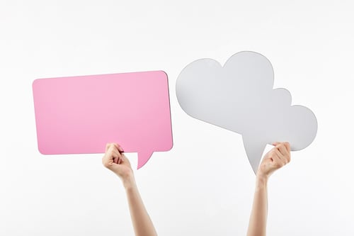 Preview: cropped view of woman with pink thought and speech bubbles in hands isolated on white