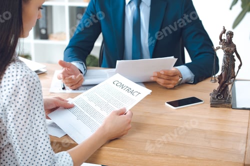 Preview: cropped shot of lawyer holding papers and client reading contract in office