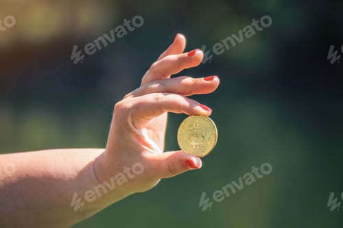 Preview: Female hand holding a bitcoin against the green background