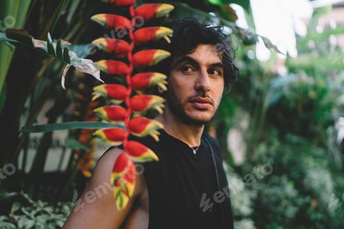 Preview: Thoughtful man standing in tropical garden near green trees