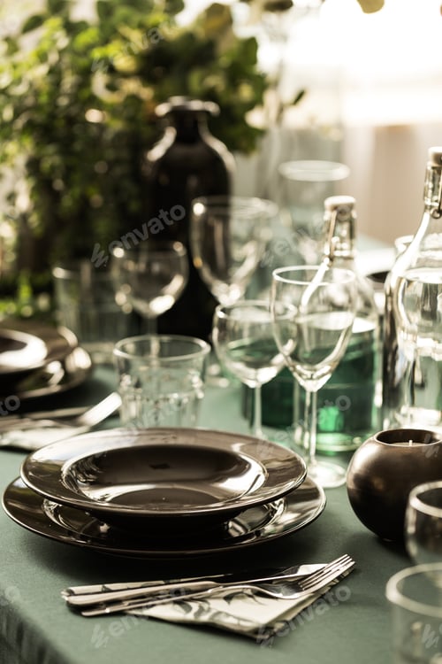 Preview: Closeup of black plate on dining room table covered with green t