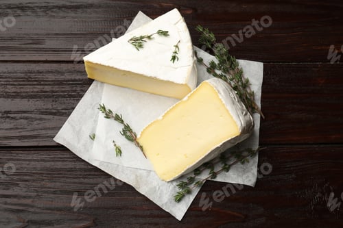 Preview: Pieces of tasty camembert cheese and thyme on wooden table, top view