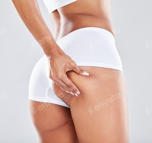 Preview: Weight, cellulite and woman touching her butt for insecurity isolated on a grey studio background.