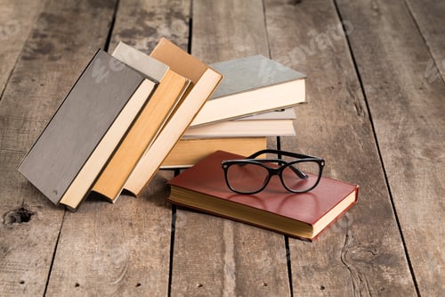 Preview: Books and reading glasses arranged on a rustic wooden table in a cozy setting