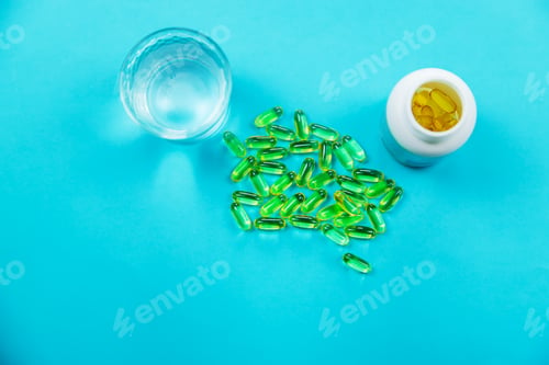 Preview: Omega 3 fish oil capsules spilling out of a bottle on a blue background.