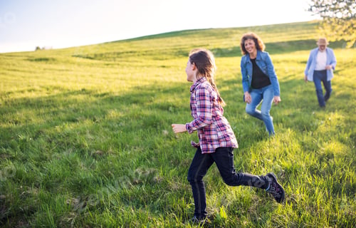 Preview: A small girl with her senior grandparents playing outside in nature.