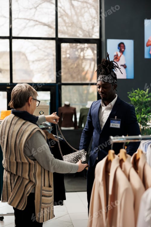 Preview: Senior customer discussing black bag material with worker,