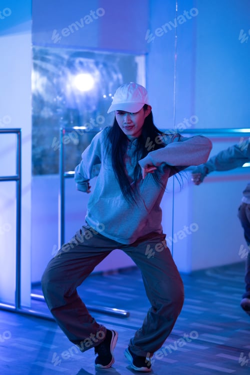 Preview: Young Asian woman practicing modern dance styles in a studio with neon light