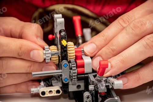 Preview: Hands making a piece of complex machinery from plastic pieces blocks constructor details