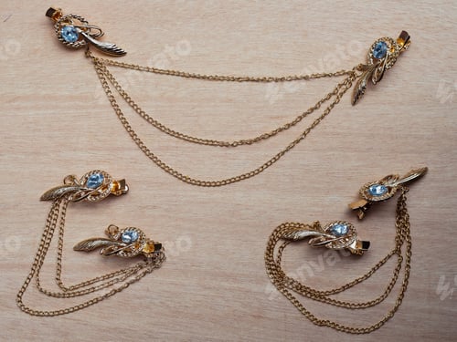 Preview: Top view of beautiful golden accessories with clips for hair on a wooden table