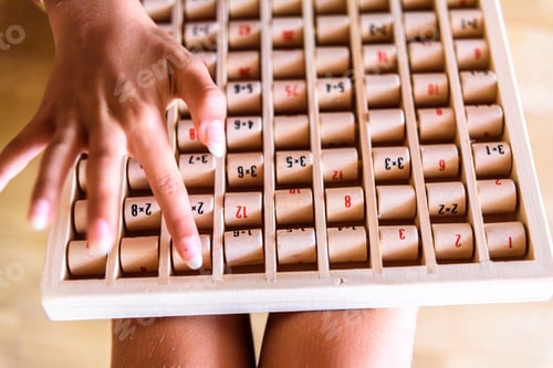 Preview: Girl using a wooden board with mathematical multiplication operations, a game to learn.