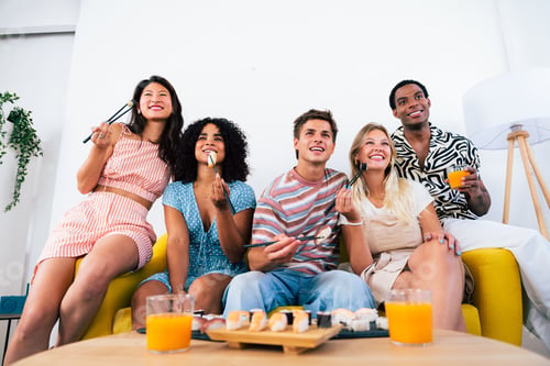 Preview: Multiethnic group of young friends meeting at home and eating sushi