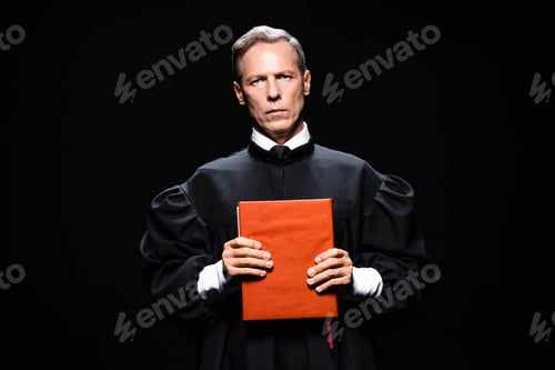 Preview: judge in judicial robe holding orange book isolated on black