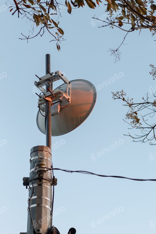 Preview: Vertical low angle shot of a radio relay antenna against a blue sky
