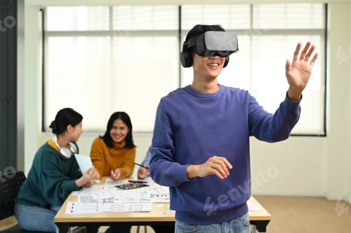 Preview: Professional developers testing virtual reality simulator glasses at meeting.