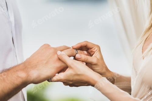 Preview: Bride putting wedding ring on groom's hand close up. Symbol of love and commitment.