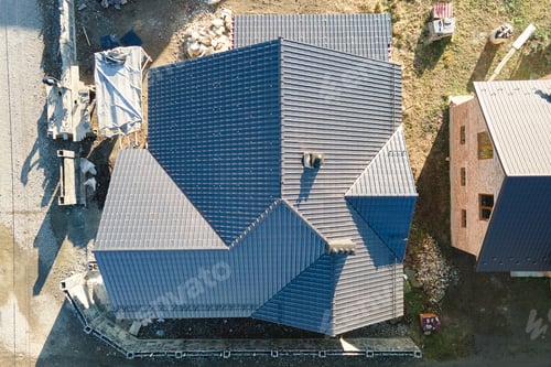 Preview: Chimney on house roof top covered with metallic shingles under construction. Tiled covering of