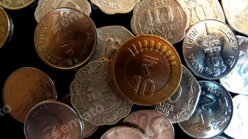 Preview: Closeup overhead shot of coins displaying Indian currency of various values on a dark background