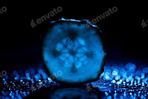 Preview: slice of cucumber with blue back light on black background