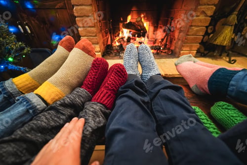 Preview: Happy family wearing warm socks in front of cozy fireplace during Christmas Time - Focus on socks