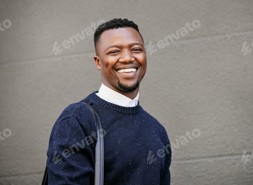 Preview: Portrait of a young businessman standing in the street in the city smiling and looking happy on a s