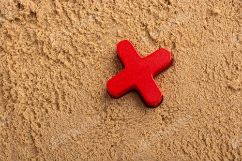 Preview: High angle of a red wooden X letter on sand