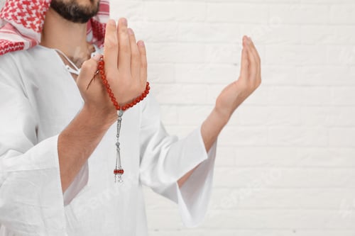 Preview: Muslim man praying near brick wall, closeup