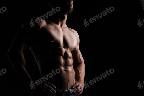 Muscular Man Shows Defined Abs on Black Background