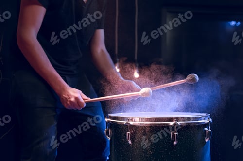 Preview: The drummer plays with mallets on floor tom in dark room.