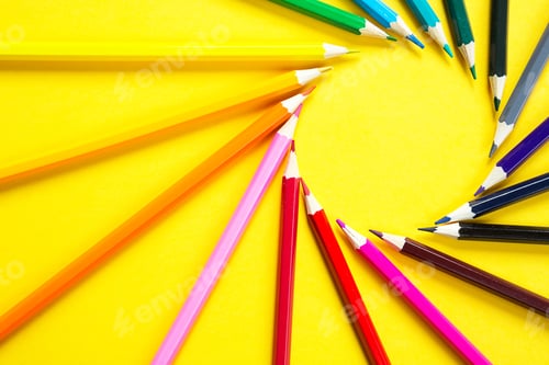 Preview: Set of colorful pencils on a yellow background is laid out in a circle in the shape of the sun