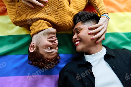 Preview: Happy gay couple lying on a lgtb rainbow flag