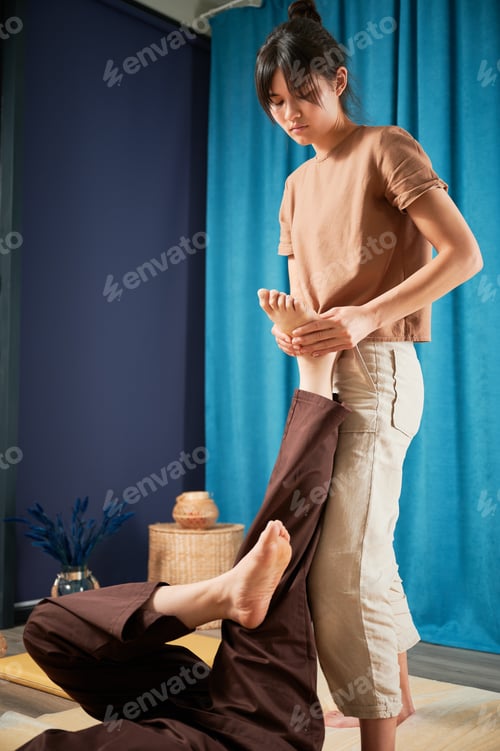 Preview: Masseuse making thai yoga massage. Woman therapist doing traditional massage treatment for patient.