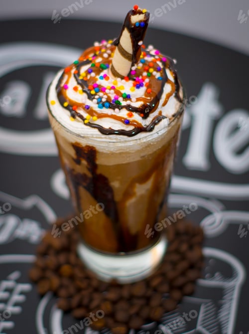 Preview: Vertical shot of a glass of iced coffee with cream and sprinkles on the table