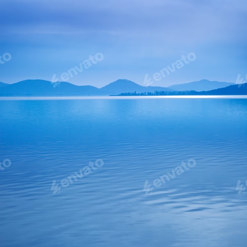 Preview: Water surface in a blue morning on the Trasimeno lake, Italy. Hills on background