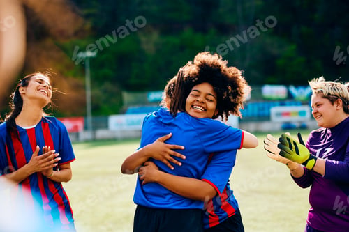 Preview: Happy female soccer players congratulating each other on their victory at the stadium.