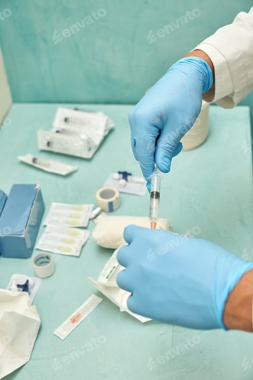 Preview: Close up of hand in rubber glove filling syringe