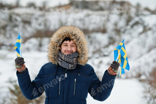 Preview: Scandinavian man with Sweden flag in winter swedish landscape.