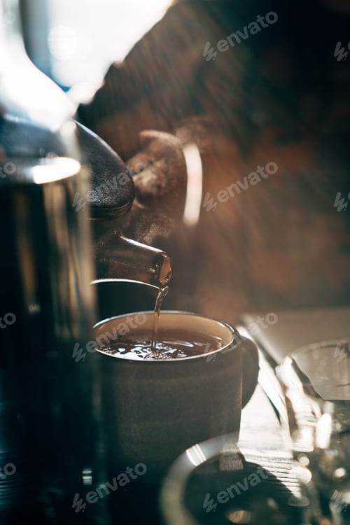 Preview: woman pouring hot tea into a cup