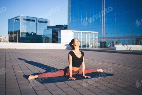Preview: Sportive fitness girl stretching out during workout warm up at city urban setting