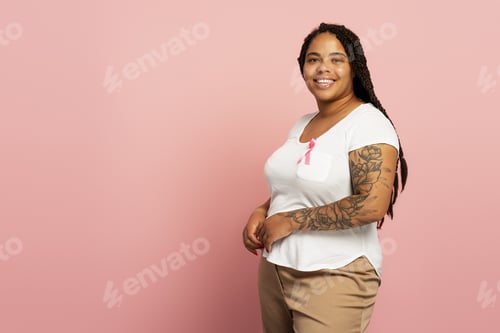 Preview: Smiling woman wearing pink ribbon showing support for breast cancer awareness