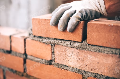 Preview: Close up of industrial bricklayer installing bricks on construction site