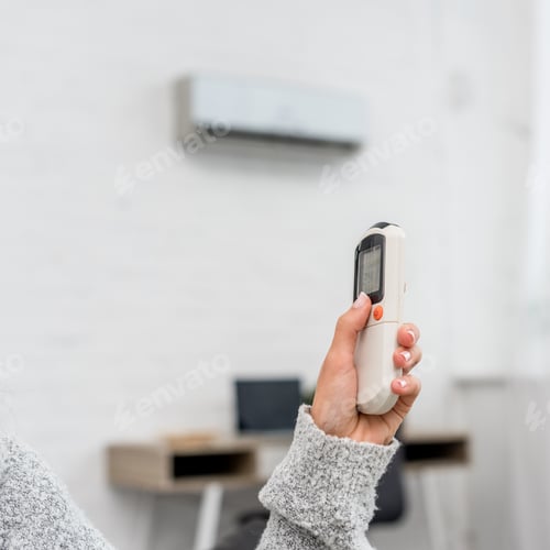 Preview: cropped shot of woman in sweater holding air conditioner remote control