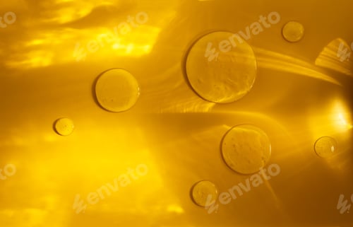Preview: round drops of transparent gel serum on a yellow background with sun glare