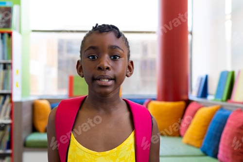Preview: Portrait of happy african american schoolgirl with school bag over couch with colourful pillows