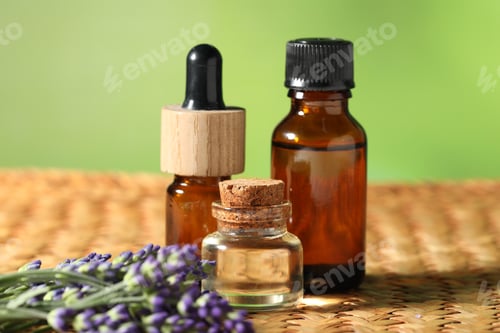 Preview: Bottles of lavender essential oil and flowers on wicker table, closeup