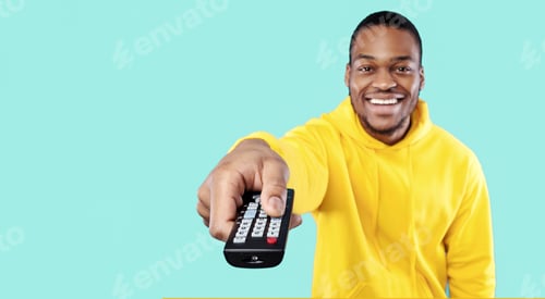 Preview: Cheerful Black Guy Watching TV Pointing Remote Controller, Blue Background