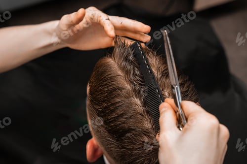 Preview: Stylist cuts man hair using comb and scissors in barbershop