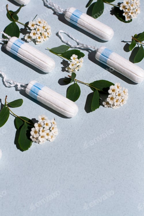 Preview: Medical female tampon and white flowers on a blue background.