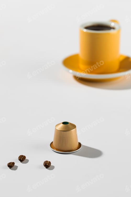 Preview: Coffee capsule with a cup and saucer in the background