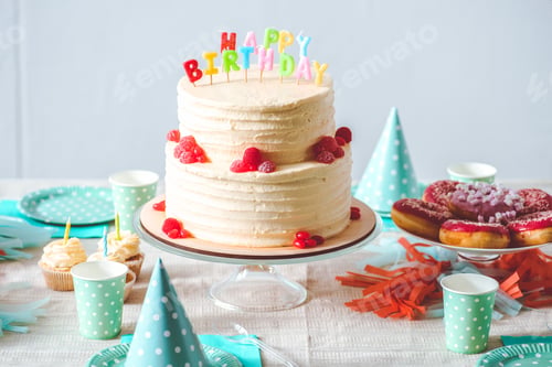 Preview: delicious birthday cake with cupcakes, doughnuts and paper cups on festive table